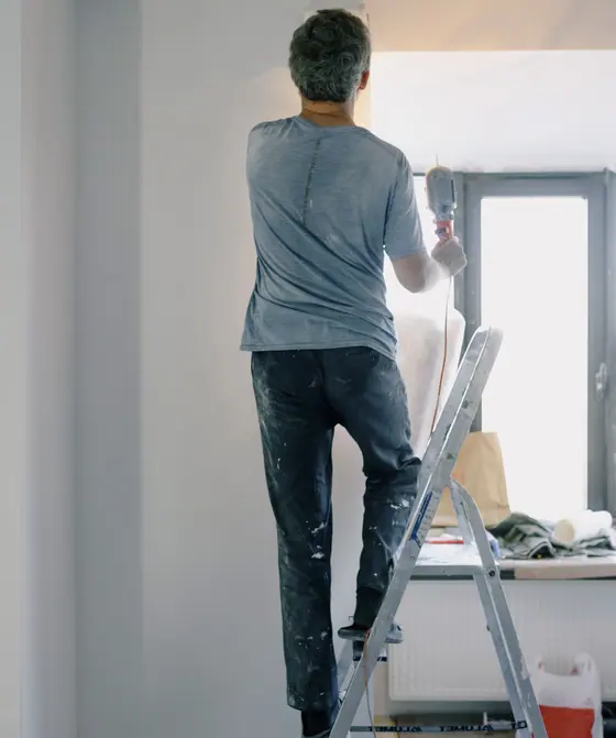 Handwerker auf einer Leiter renoviert eine Wohnung